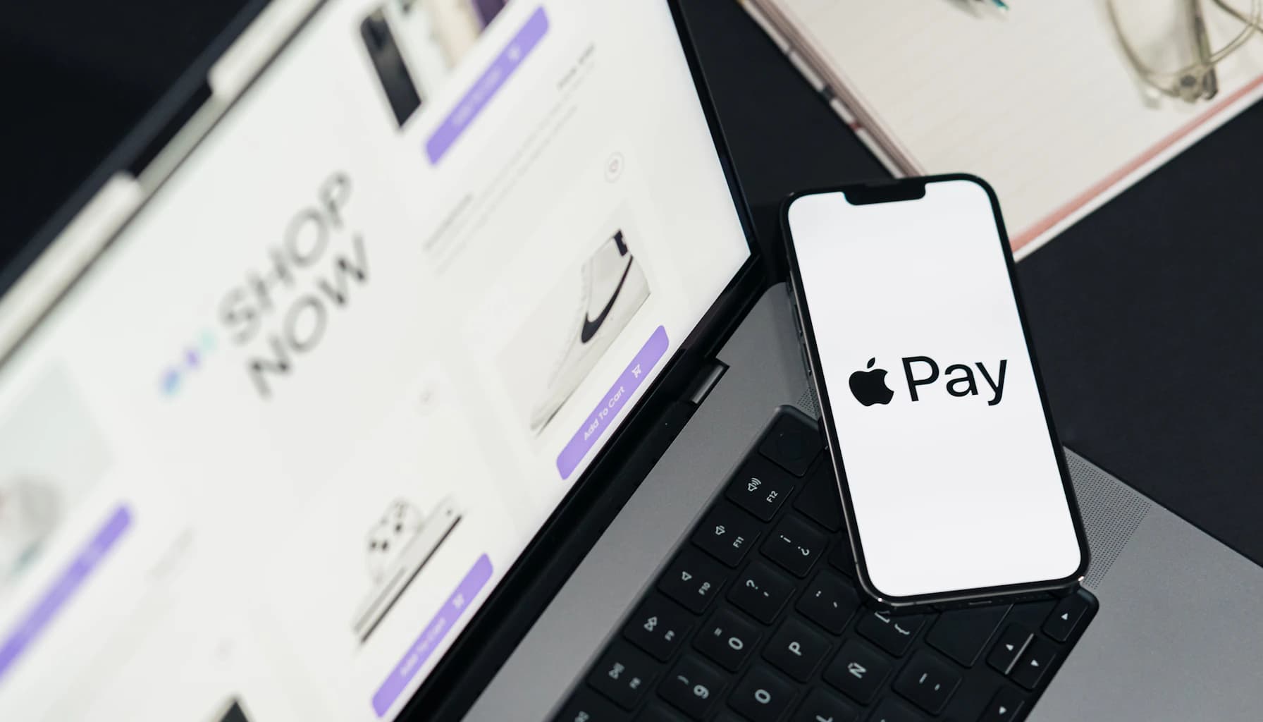 Apple Pay shown on a phone screen with a laptop displaying an e-commerce site, illustrating payment methods in WooCommerce.