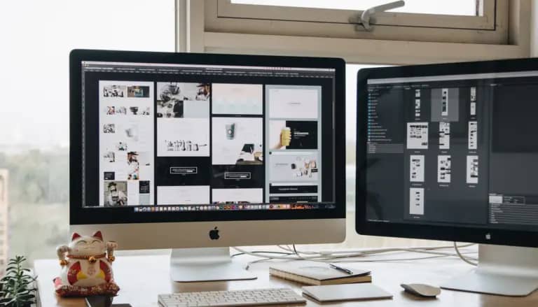 Two monitors setup next to each other on a computer desk.