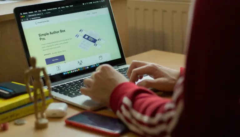 person using macbook pro on brown wooden table
